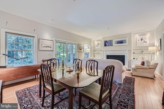 dining room featuring built in features, light hardwood / wood-style floors, and crown molding