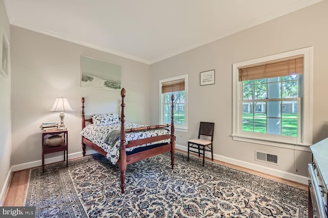 bedroom featuring ornamental molding, multiple windows, and hardwood / wood-style floors