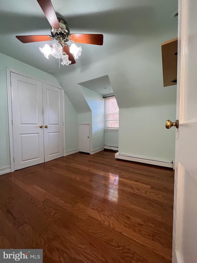 additional living space with ceiling fan, vaulted ceiling, dark hardwood / wood-style flooring, and a baseboard heating unit