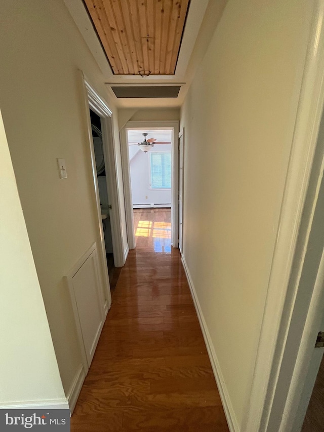 corridor with dark wood-type flooring, wood ceiling, and a baseboard radiator