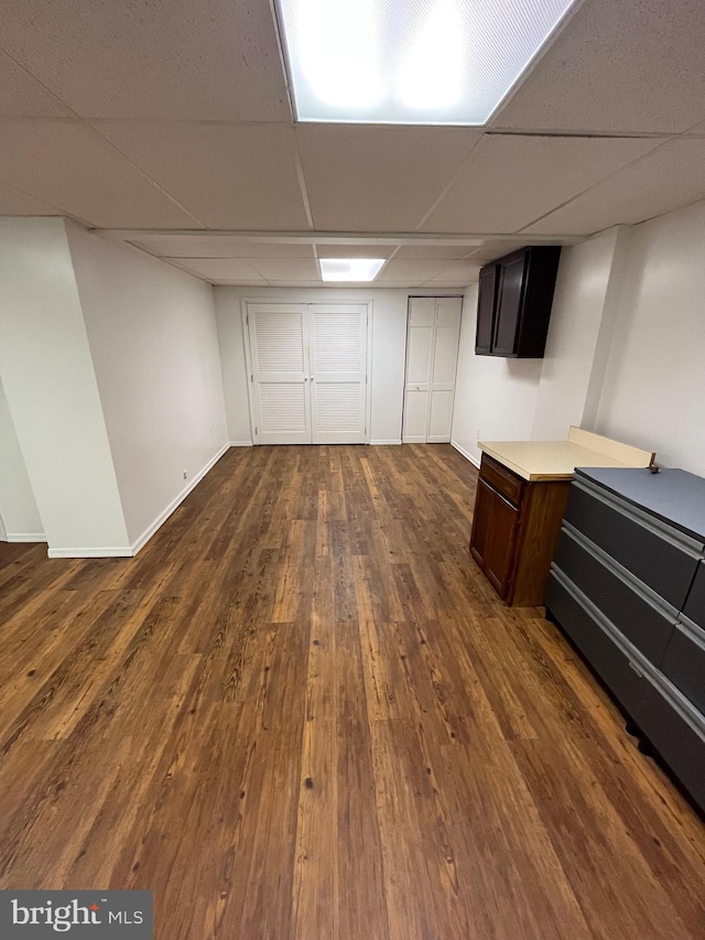 basement featuring a drop ceiling and dark wood-type flooring