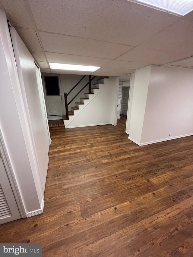 basement featuring dark wood-type flooring and a drop ceiling