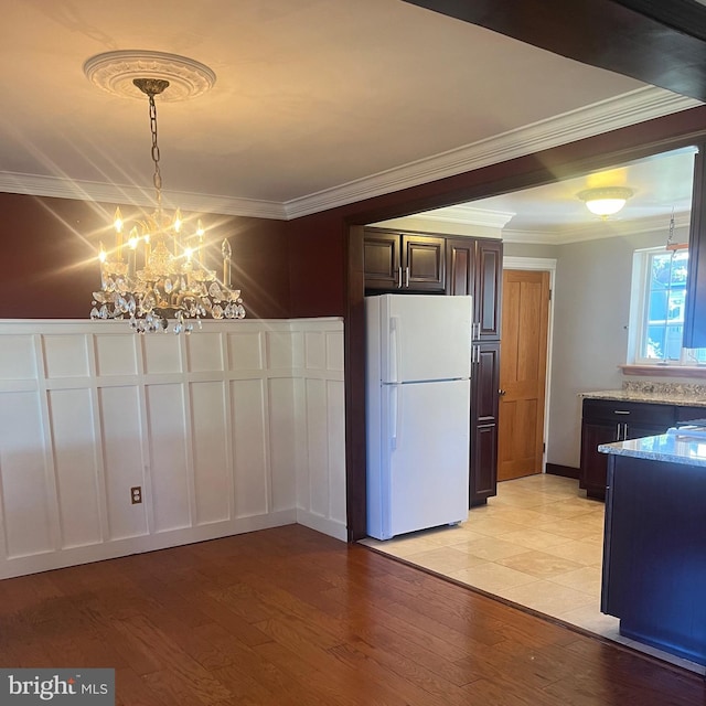 kitchen with light hardwood / wood-style flooring, ornamental molding, dark brown cabinets, and white refrigerator