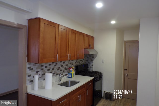 kitchen featuring decorative backsplash, gas stove, dark wood-type flooring, and sink