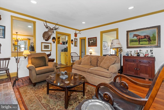 living room with crown molding, wood-type flooring, and a chandelier