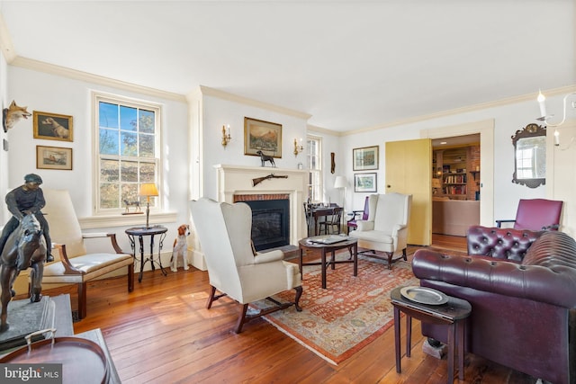 living room featuring ornamental molding, a brick fireplace, and wood-type flooring