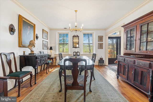 dining area with ornamental molding, light hardwood / wood-style flooring, and an inviting chandelier