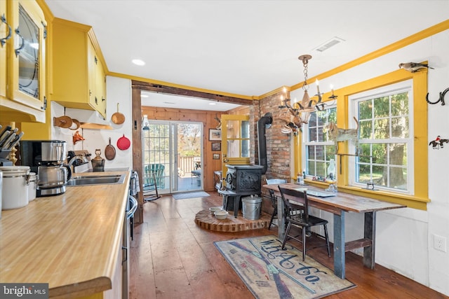 kitchen featuring a healthy amount of sunlight, a wood stove, an inviting chandelier, and pendant lighting