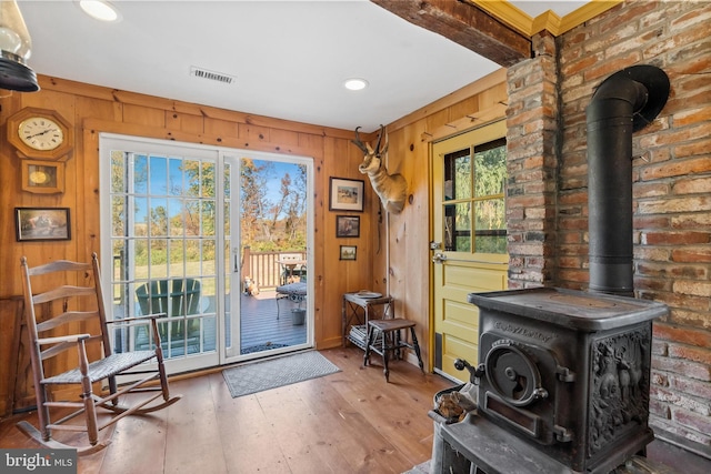 entryway with a wealth of natural light, beam ceiling, hardwood / wood-style flooring, and a wood stove