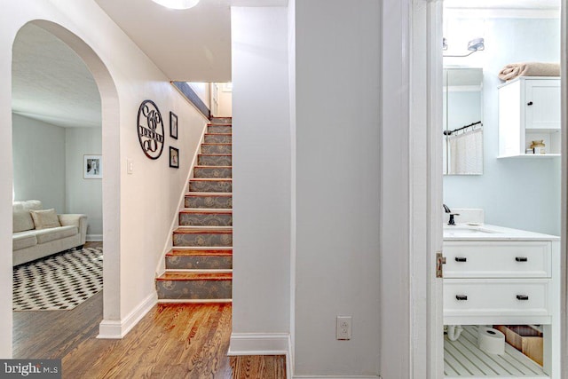 staircase featuring hardwood / wood-style floors and sink