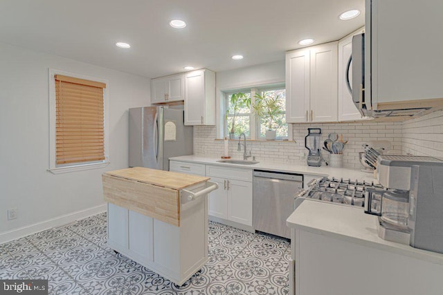 kitchen with butcher block counters, sink, white cabinetry, appliances with stainless steel finishes, and tasteful backsplash