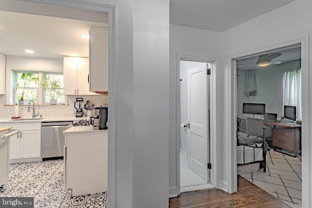 kitchen with dishwasher, sink, backsplash, white cabinetry, and light hardwood / wood-style floors