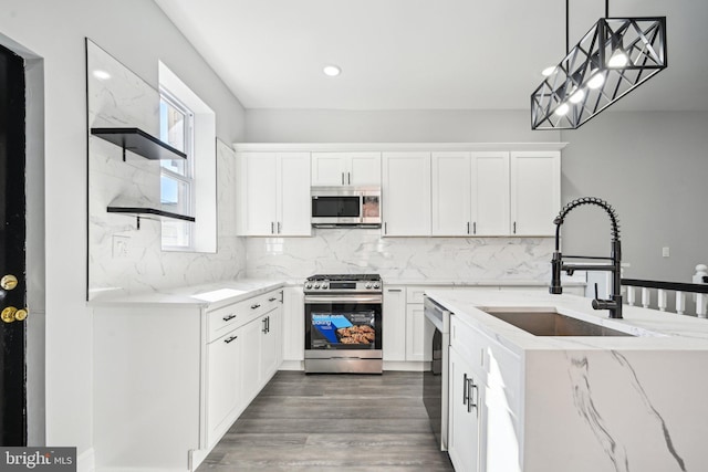 kitchen featuring dark hardwood / wood-style flooring, decorative light fixtures, sink, appliances with stainless steel finishes, and white cabinetry