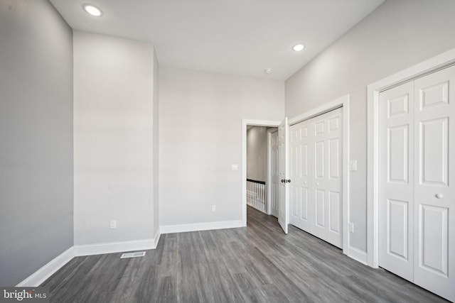 unfurnished bedroom with dark hardwood / wood-style floors and multiple closets