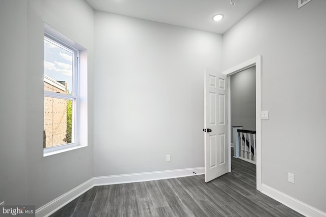 empty room with a wealth of natural light and dark hardwood / wood-style floors