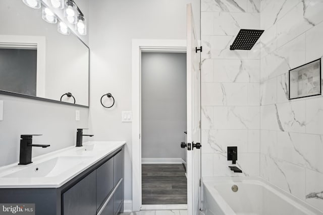 bathroom with hardwood / wood-style floors, tiled shower / bath combo, and vanity