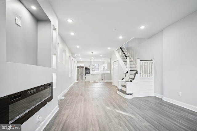 unfurnished living room featuring a notable chandelier and wood-type flooring