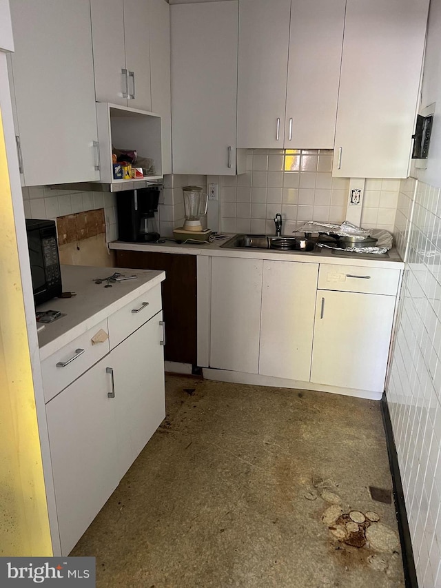 kitchen with backsplash, sink, and white cabinetry