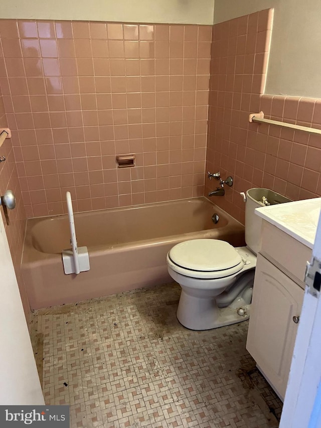 full bathroom with vanity, tile walls, tiled shower / bath combo, and toilet