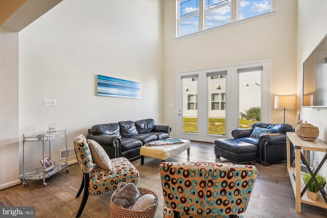 living room featuring wood-type flooring, a high ceiling, and plenty of natural light