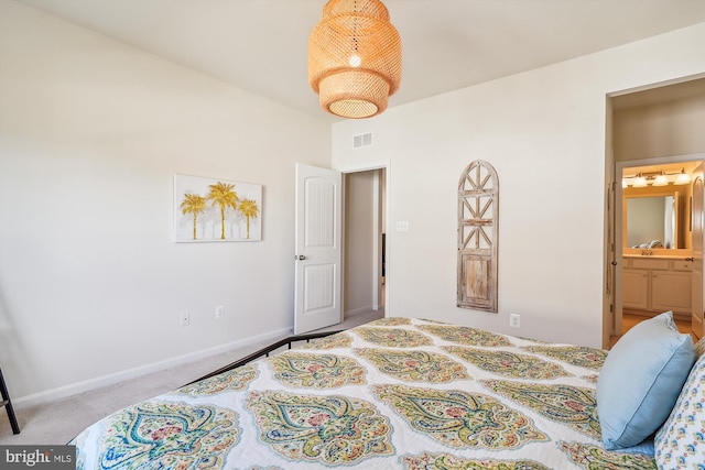 bedroom with connected bathroom and light carpet