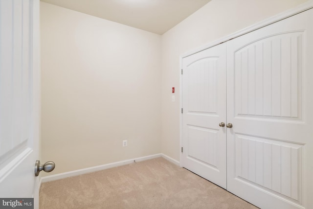 unfurnished bedroom with light carpet and a closet