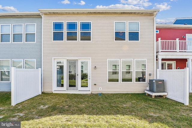 rear view of property featuring a balcony, french doors, central air condition unit, and a lawn