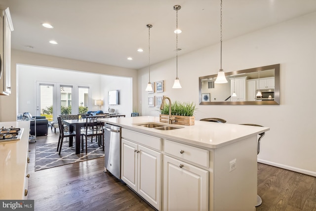 kitchen with sink, stainless steel appliances, white cabinets, dark wood-type flooring, and a kitchen island with sink