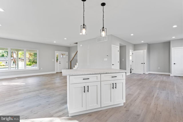 kitchen featuring white cabinets, pendant lighting, light stone counters, and light hardwood / wood-style flooring