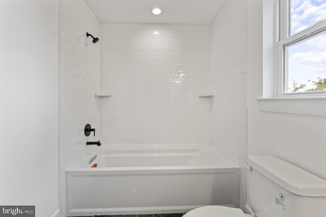 bathroom with toilet and tiled shower / bath