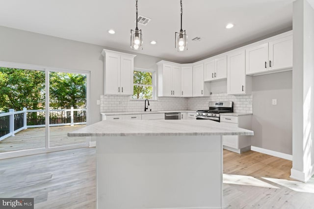 kitchen featuring pendant lighting, white cabinetry, stainless steel appliances, and a wealth of natural light