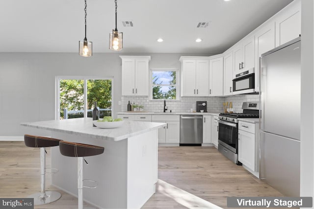 kitchen featuring a wealth of natural light, white cabinets, light hardwood / wood-style floors, and appliances with stainless steel finishes