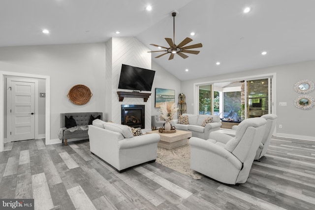 living room featuring a large fireplace, ceiling fan, high vaulted ceiling, and light hardwood / wood-style flooring