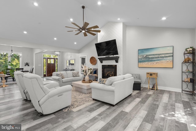 living room featuring ceiling fan, high vaulted ceiling, light hardwood / wood-style flooring, and a fireplace