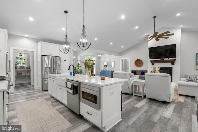 kitchen featuring appliances with stainless steel finishes, white cabinetry, sink, and an island with sink