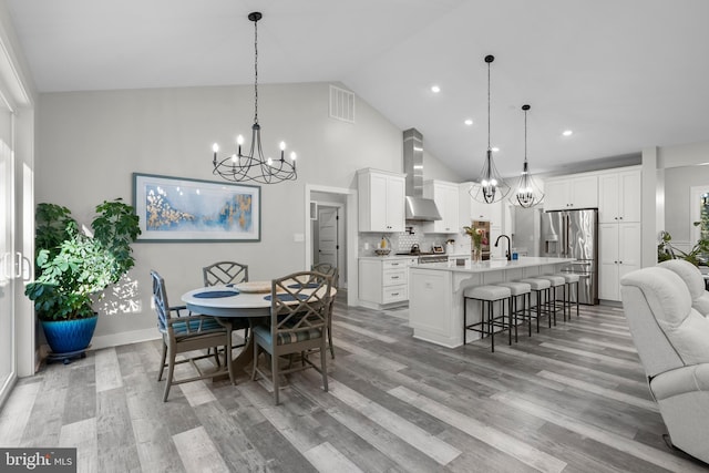 dining space featuring light hardwood / wood-style floors and high vaulted ceiling