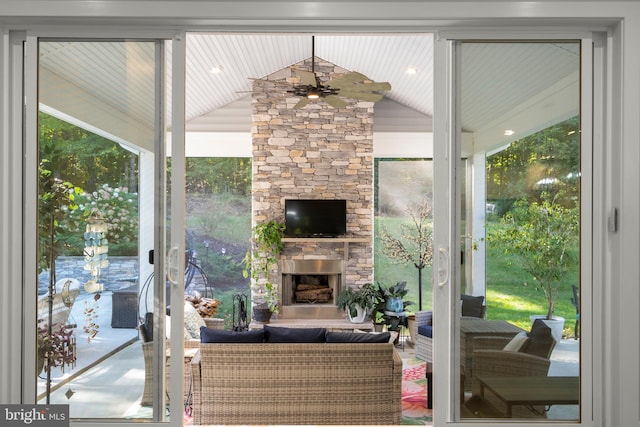 interior space with vaulted ceiling, ceiling fan, and an outdoor stone fireplace