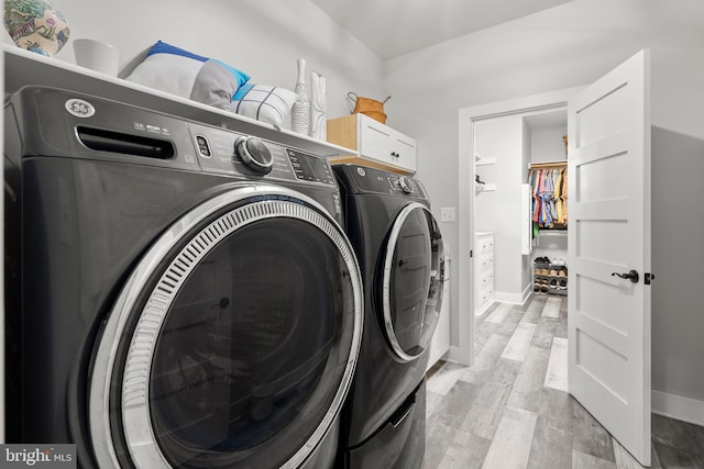 laundry room with cabinets, light hardwood / wood-style flooring, and washing machine and clothes dryer