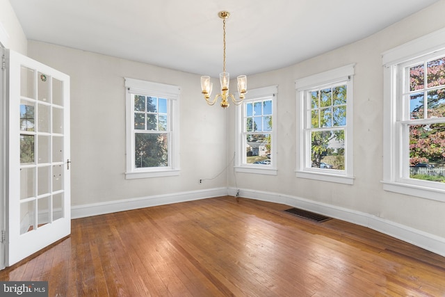 unfurnished dining area with a notable chandelier and hardwood / wood-style floors