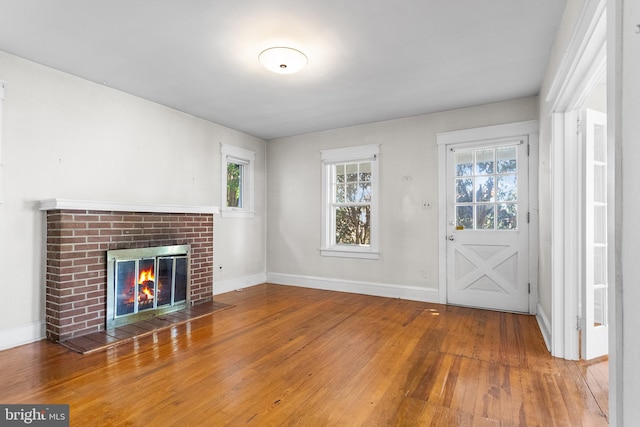 unfurnished living room with a brick fireplace and wood-type flooring