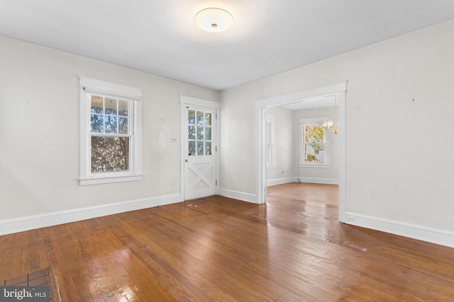 empty room featuring hardwood / wood-style flooring and a chandelier