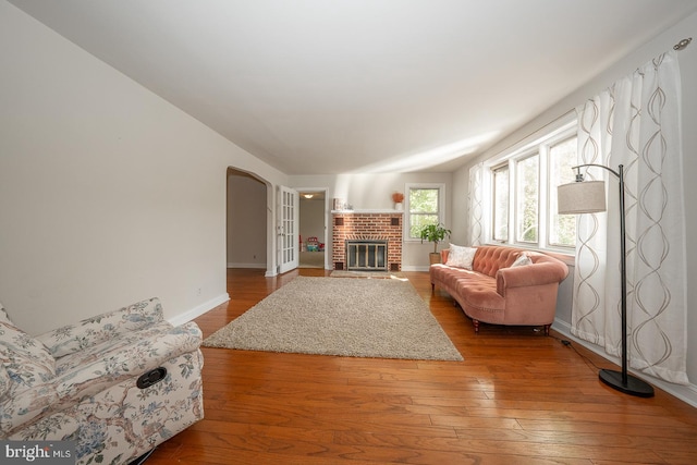 living room featuring lofted ceiling, hardwood / wood-style flooring, and a brick fireplace