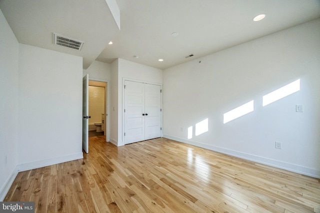 unfurnished bedroom with light wood-type flooring and a closet