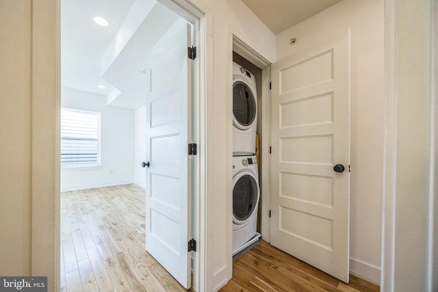 washroom with stacked washer / dryer and light hardwood / wood-style flooring