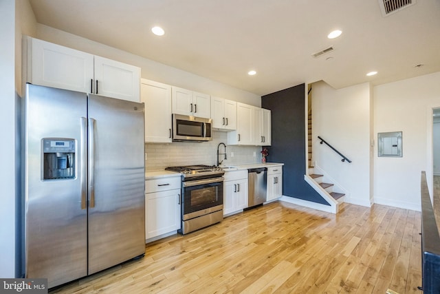 kitchen featuring white cabinets, stainless steel appliances, and light hardwood / wood-style flooring