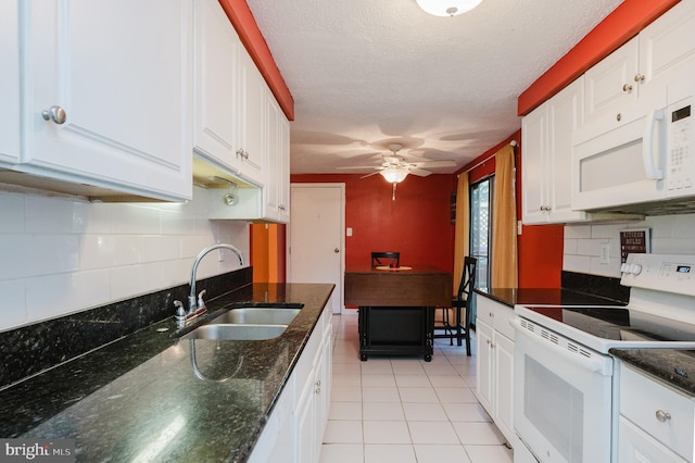 kitchen featuring dark stone countertops, sink, light tile patterned floors, white cabinetry, and white appliances