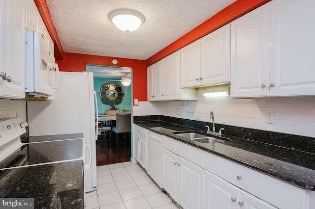 kitchen featuring white appliances, sink, white cabinetry, dark stone counters, and light tile patterned floors