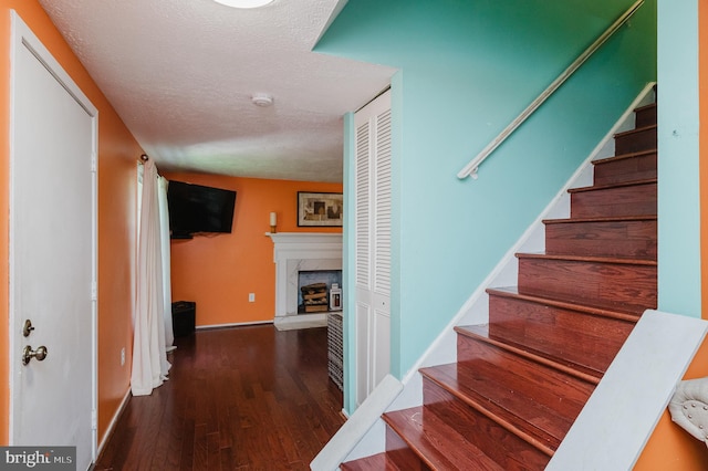 stairs featuring a textured ceiling and hardwood / wood-style floors