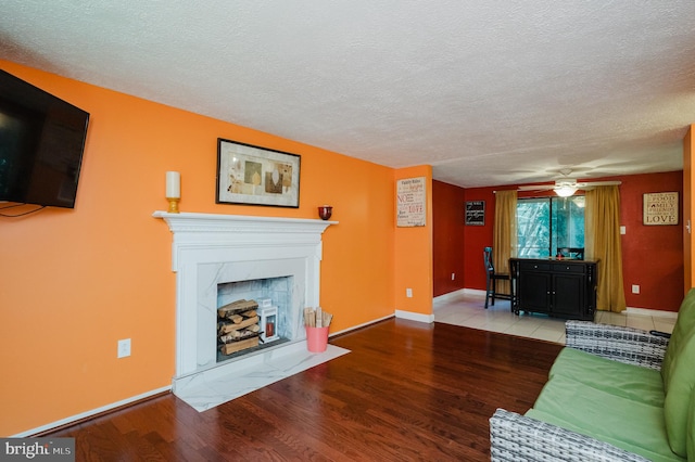 living room featuring light hardwood / wood-style flooring, a textured ceiling, and ceiling fan