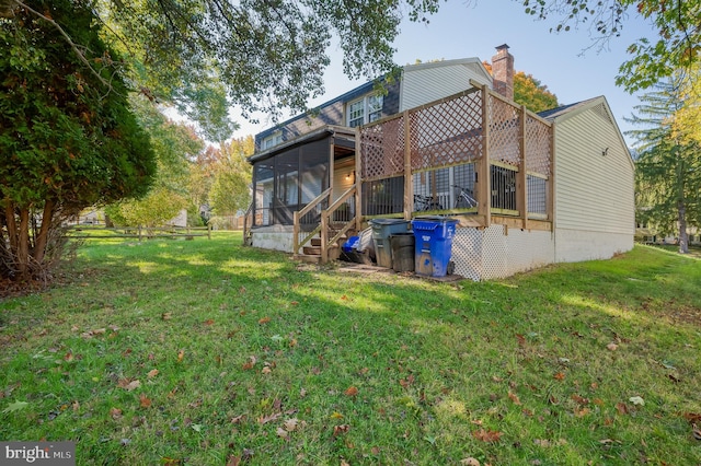 back of house featuring a sunroom and a lawn